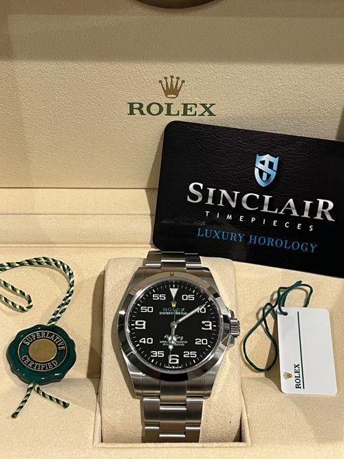 A rolex watch is in a box with a sinclair card