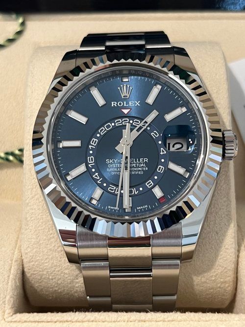 A silver rolex watch with a blue face is in a box