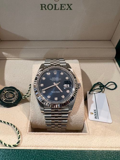 A rolex watch is in a box with a tag attached to it.