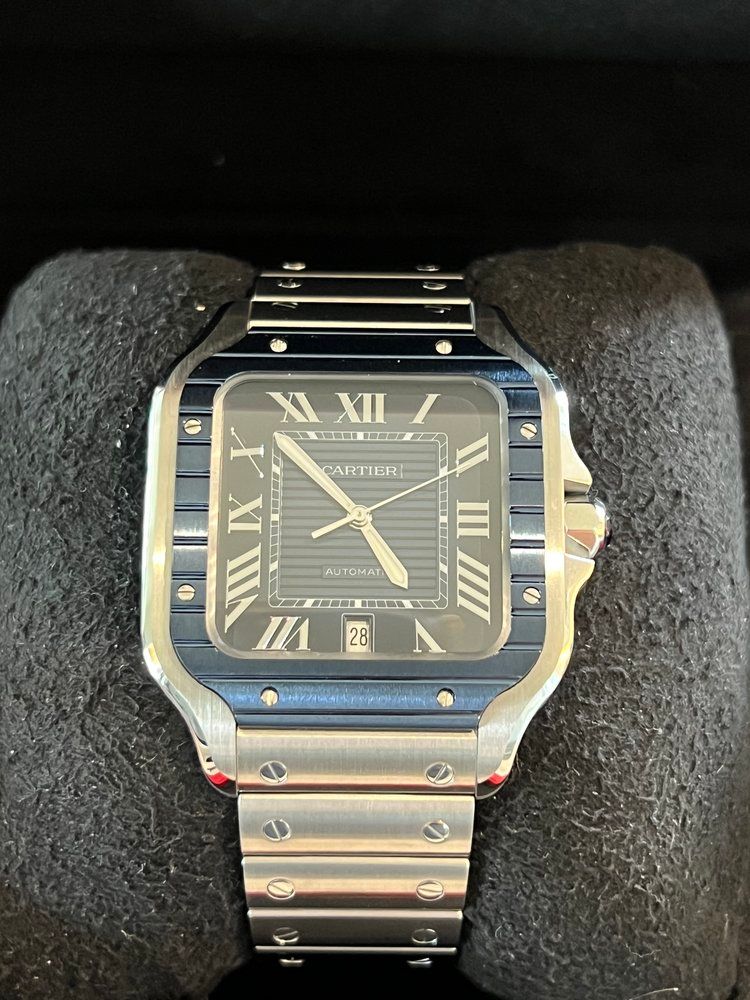 A cartier watch is sitting on a black cushion.