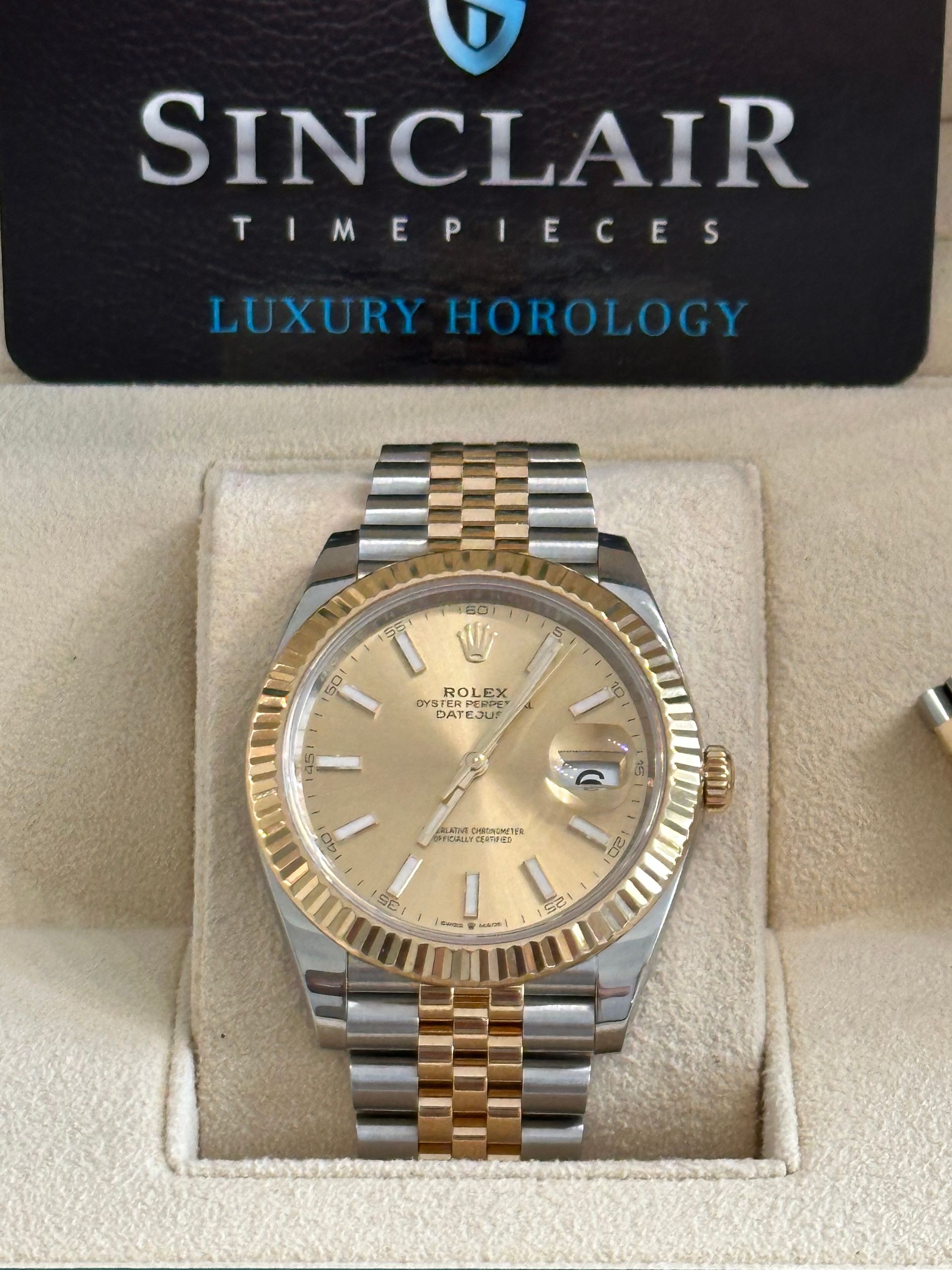 A rolex watch is sitting on top of a white cushion.