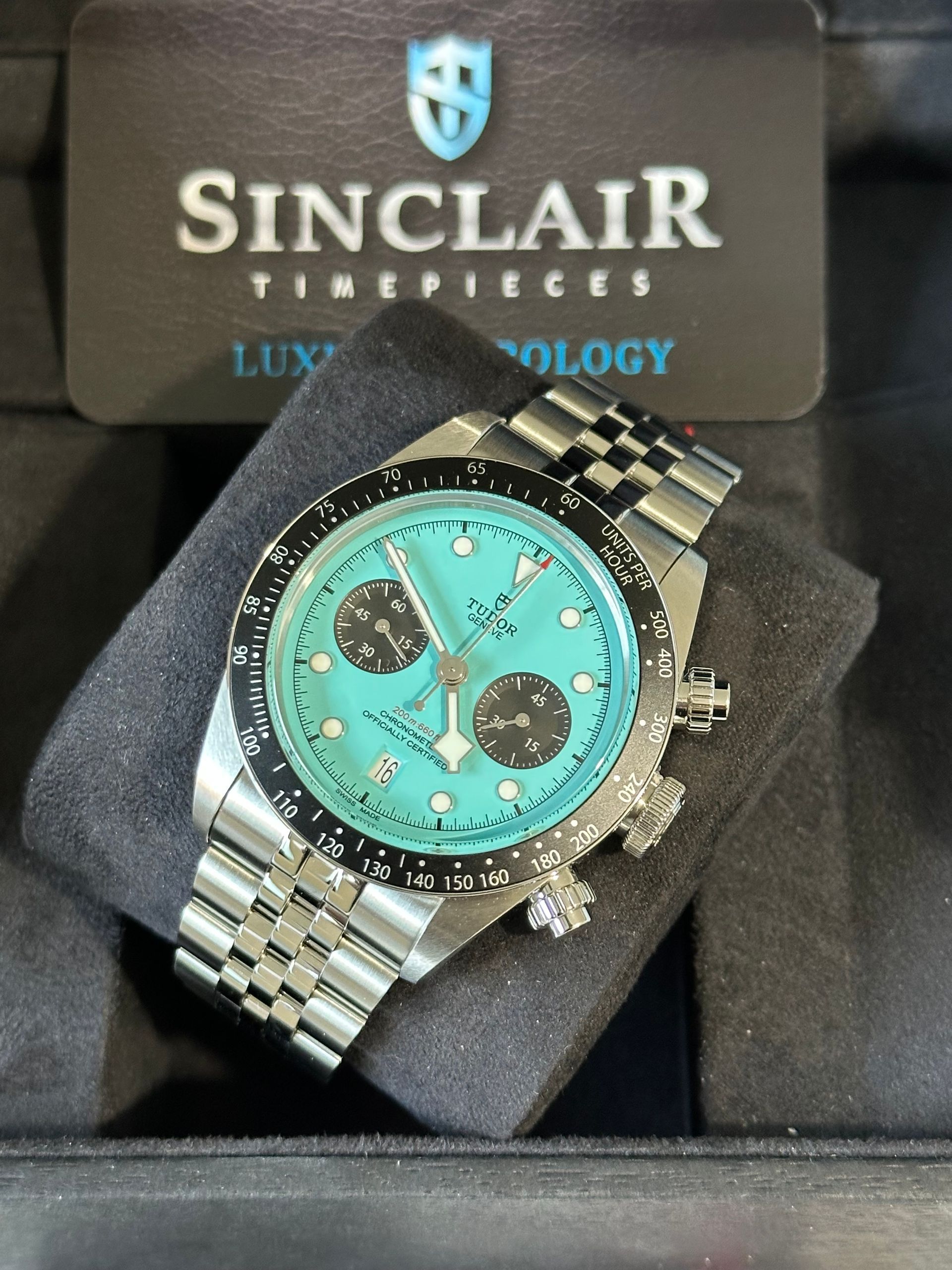 A rolex watch is in a green box on a table.