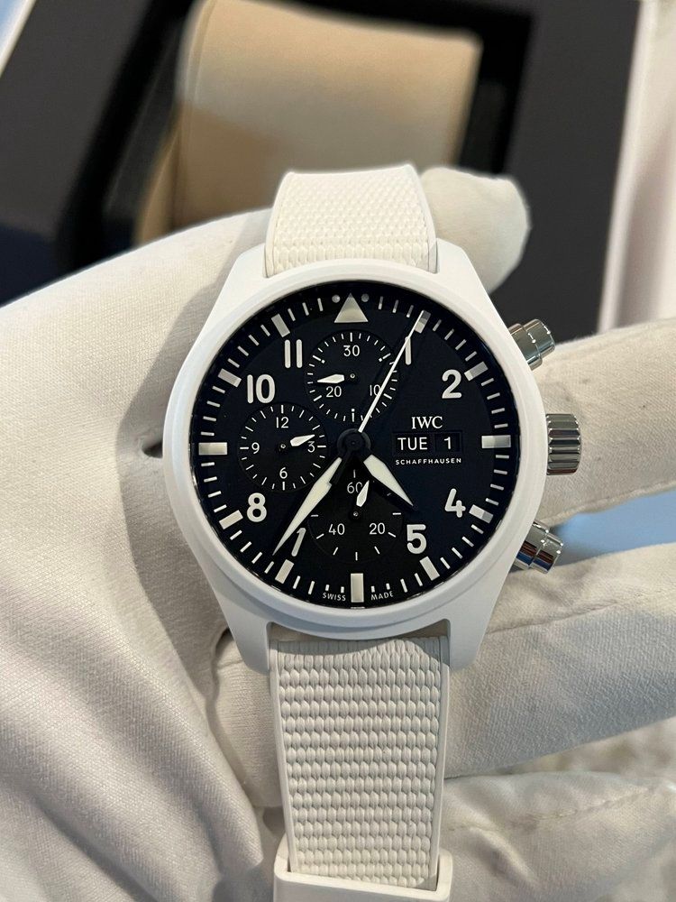 A person is holding a white watch with a black face