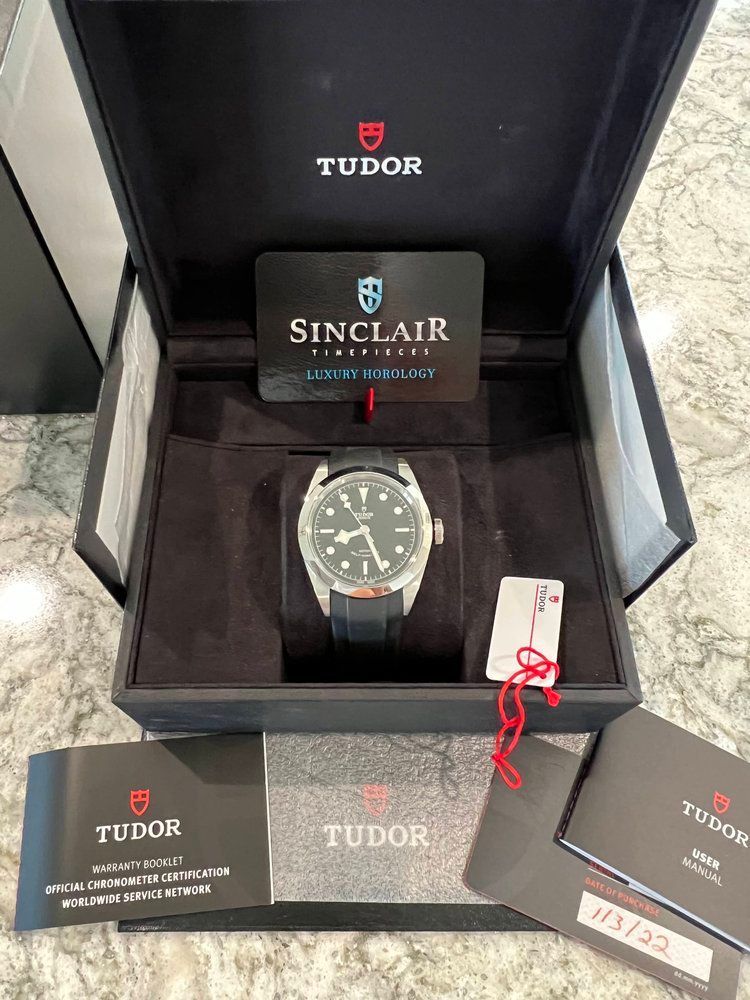 A tudor watch is in a box with a certificate.