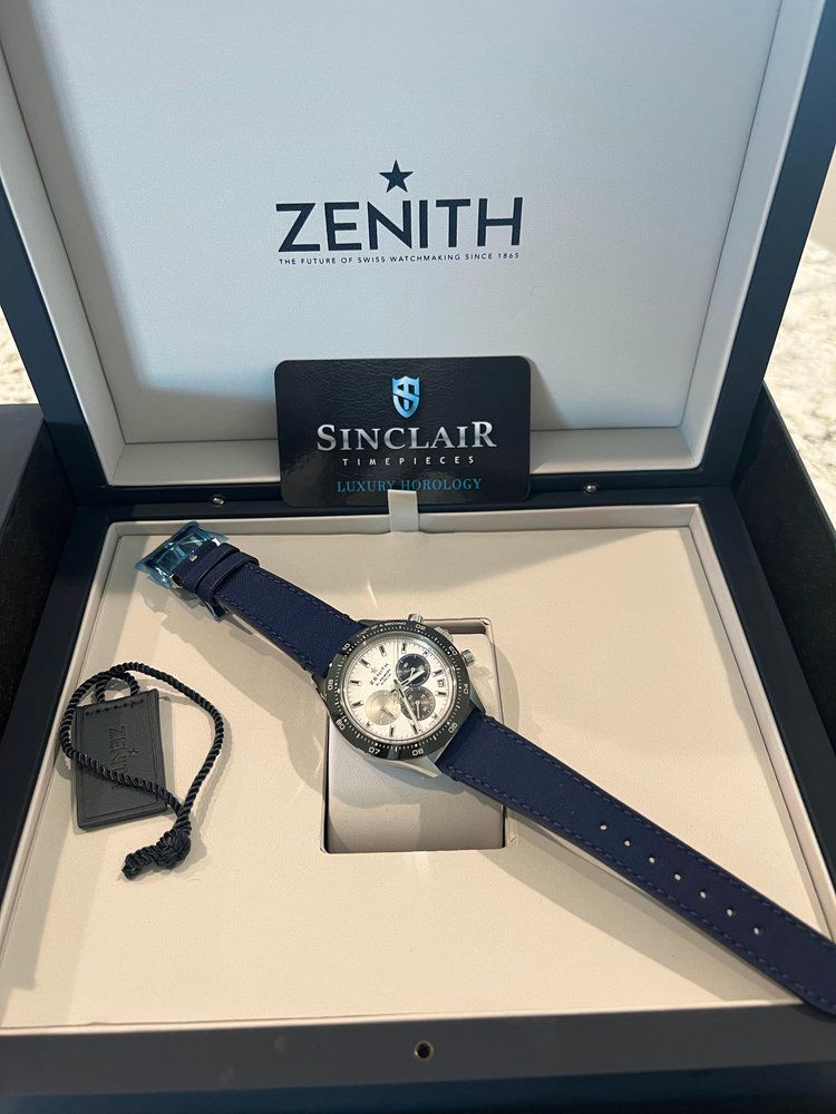 A zenith watch with a blue strap is in a box