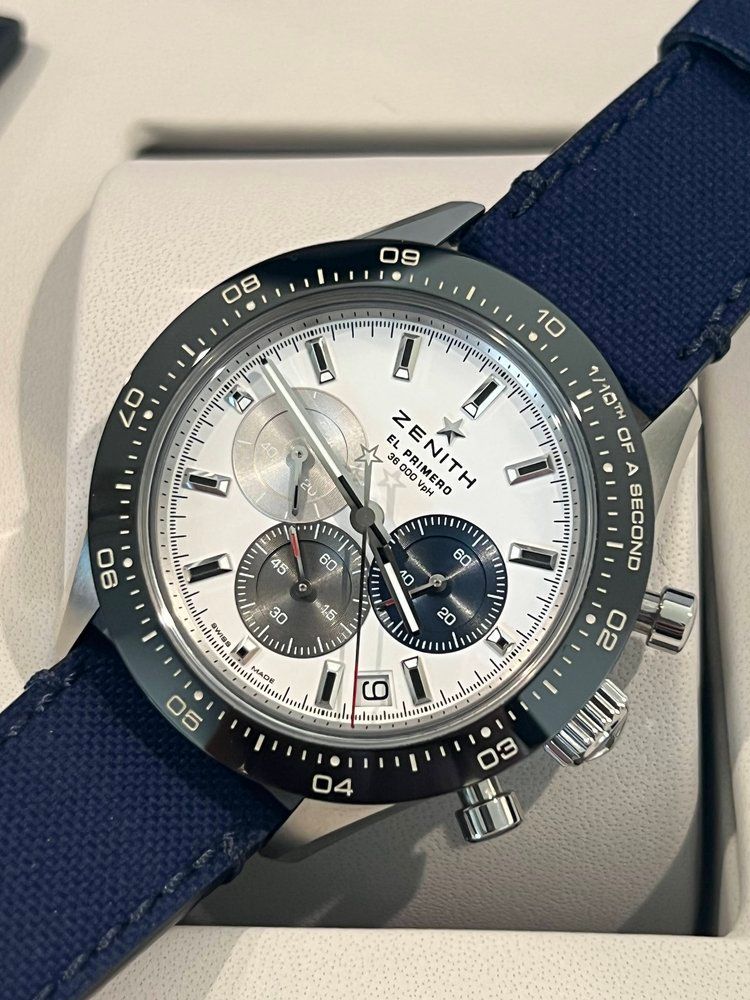 A zenith watch with a blue band is sitting in a box.