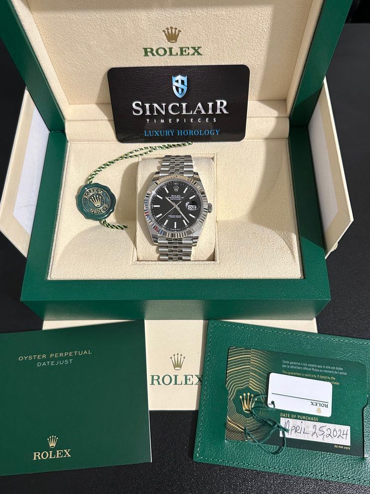A rolex watch is in a green and white box