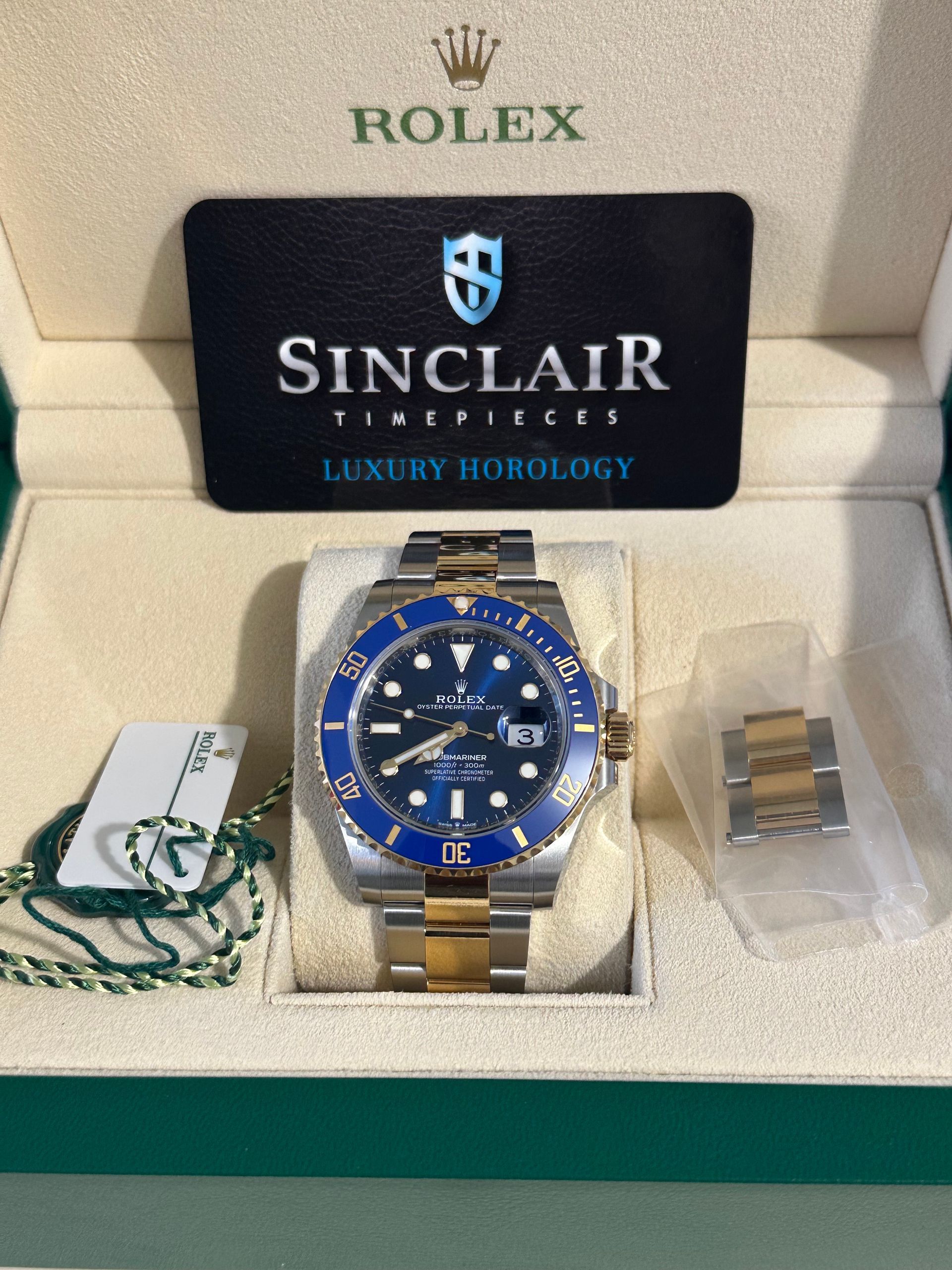 A silver and green rolex watch sits in a box