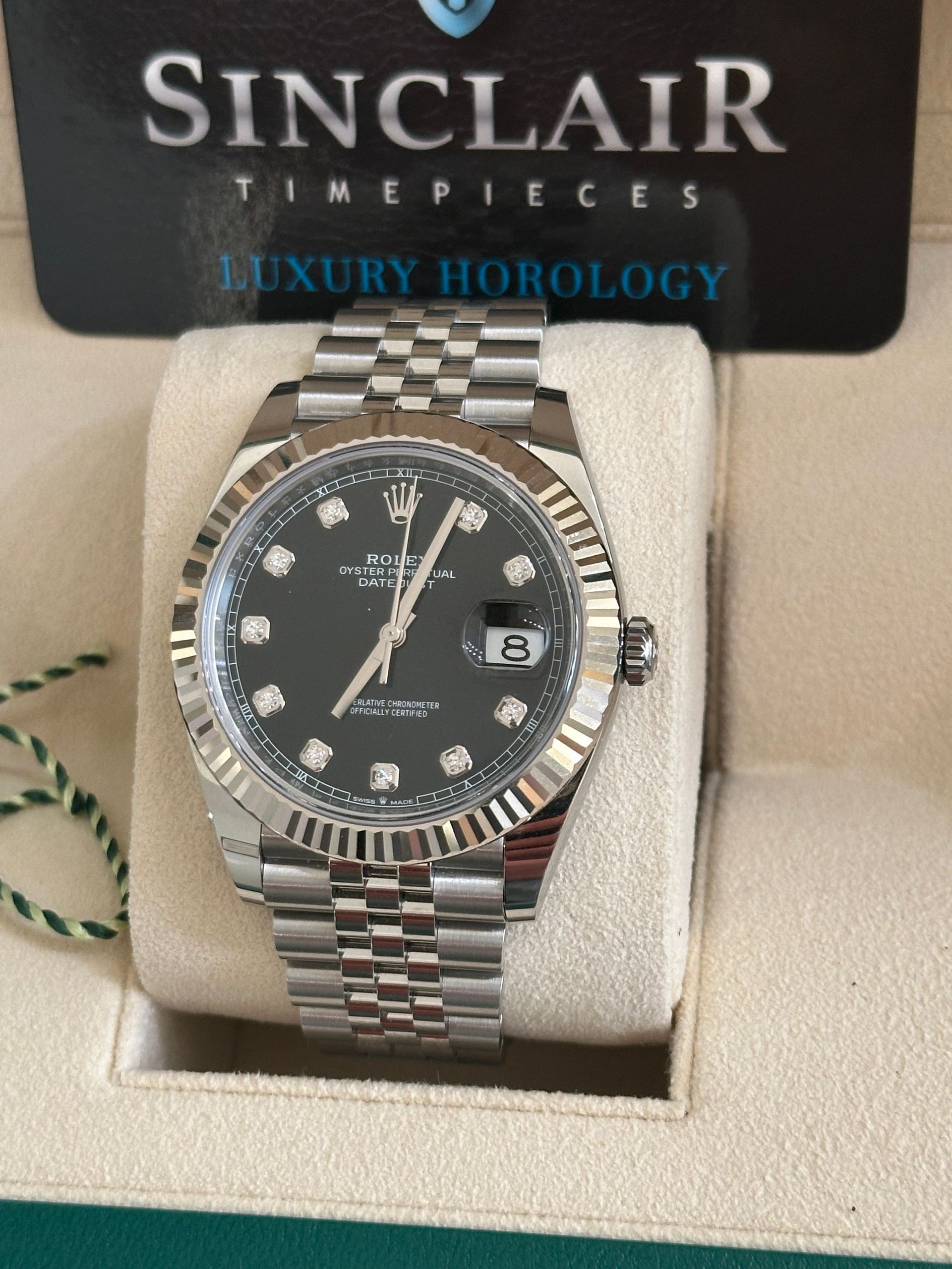 A rolex watch is in a green box on a table.