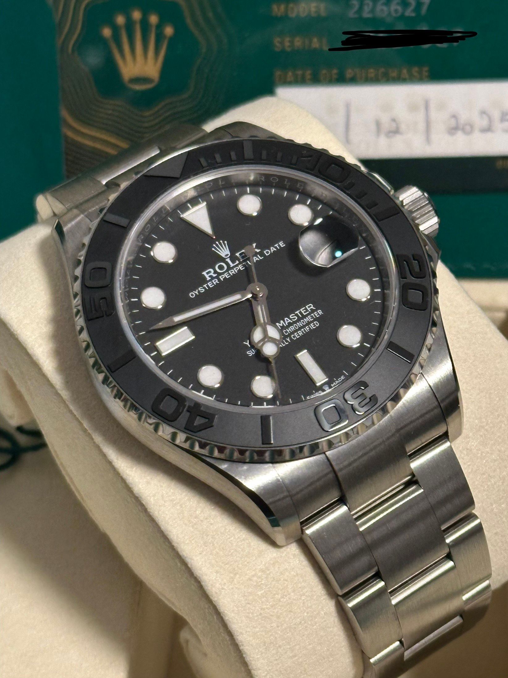 A rolex watch is in a green box on a table.