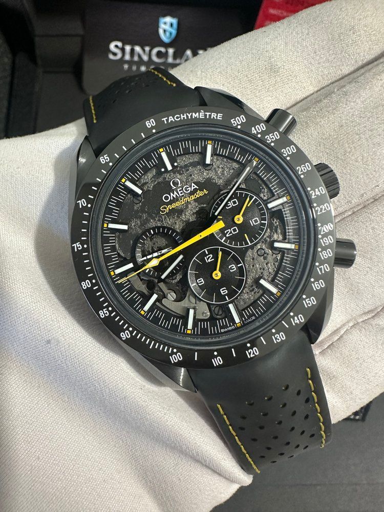 A person is holding a black and yellow omega watch.