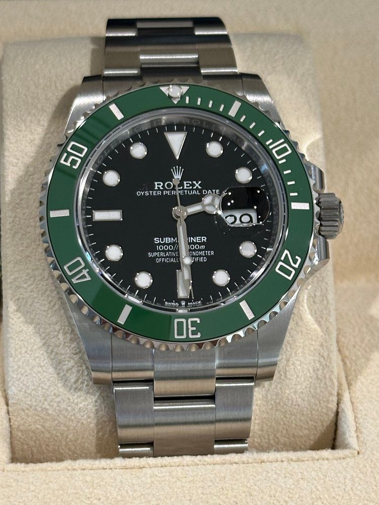 A silver rolex watch with a green face