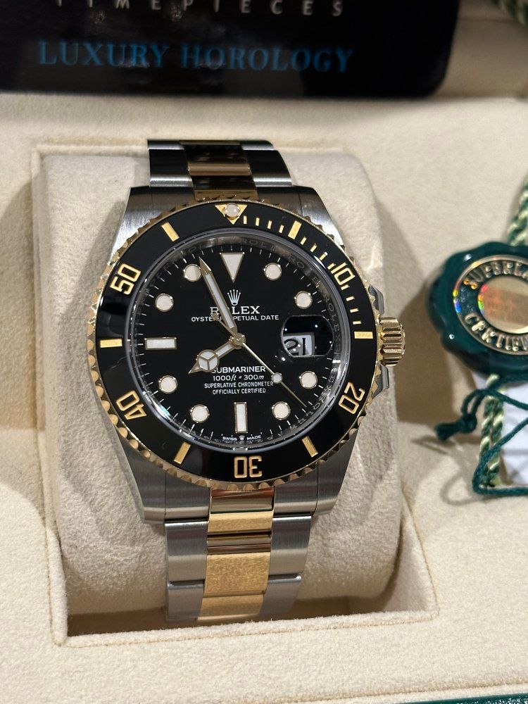 A silver and gold rolex watch with a black face