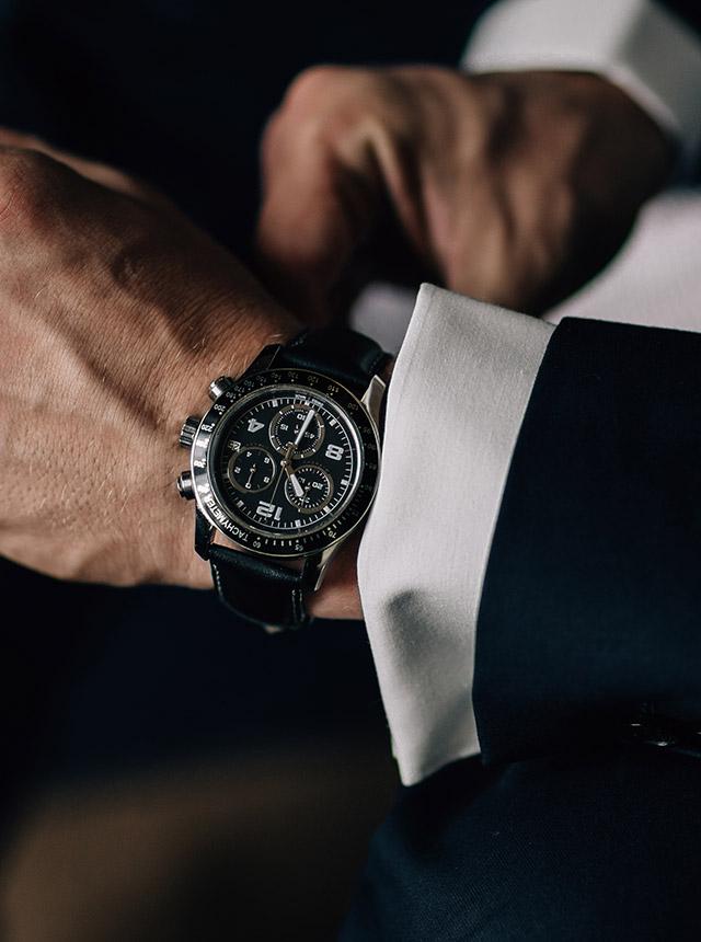 A man in a suit is looking at his watch on his wrist.