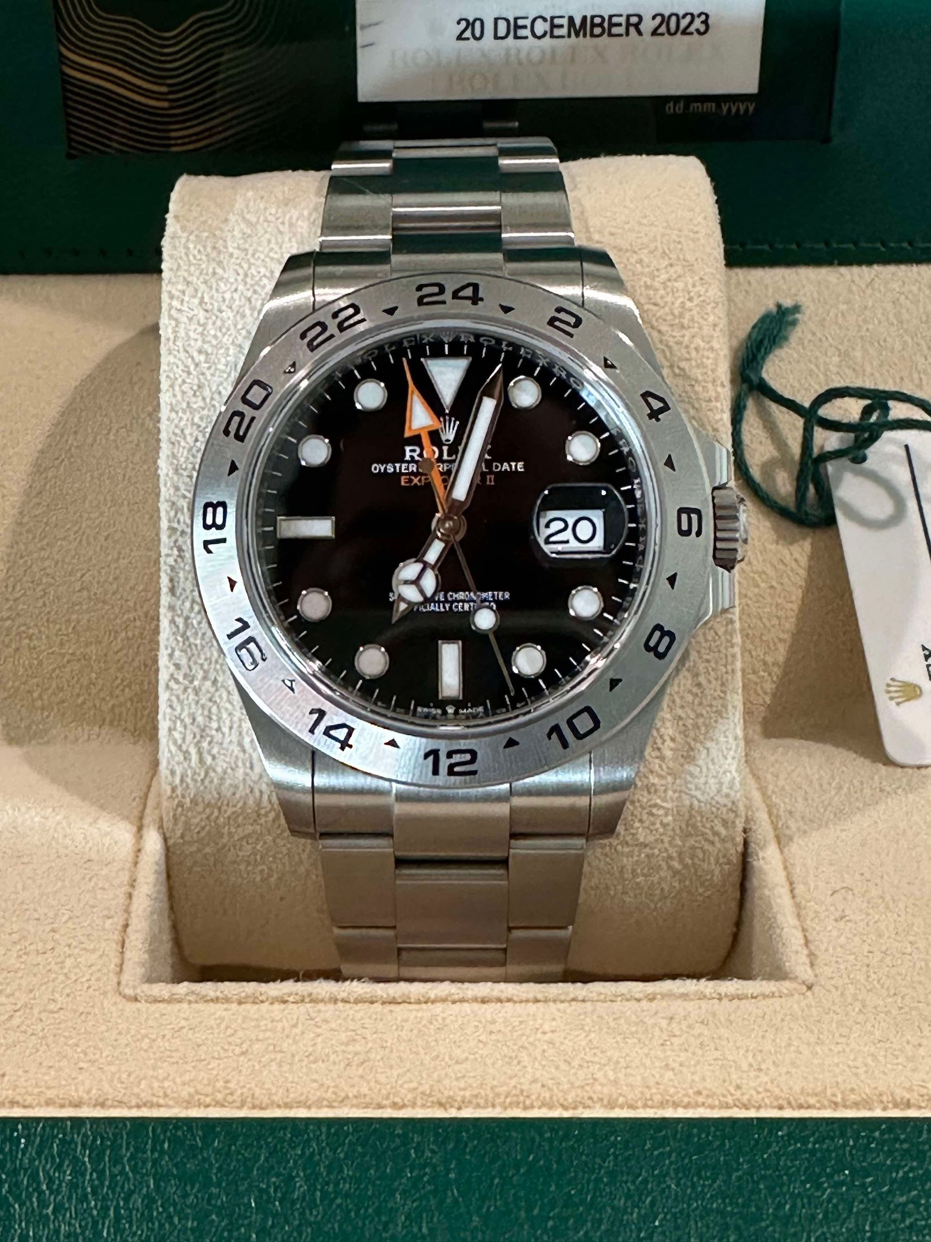 A rolex watch is in a green box with a sinclair card