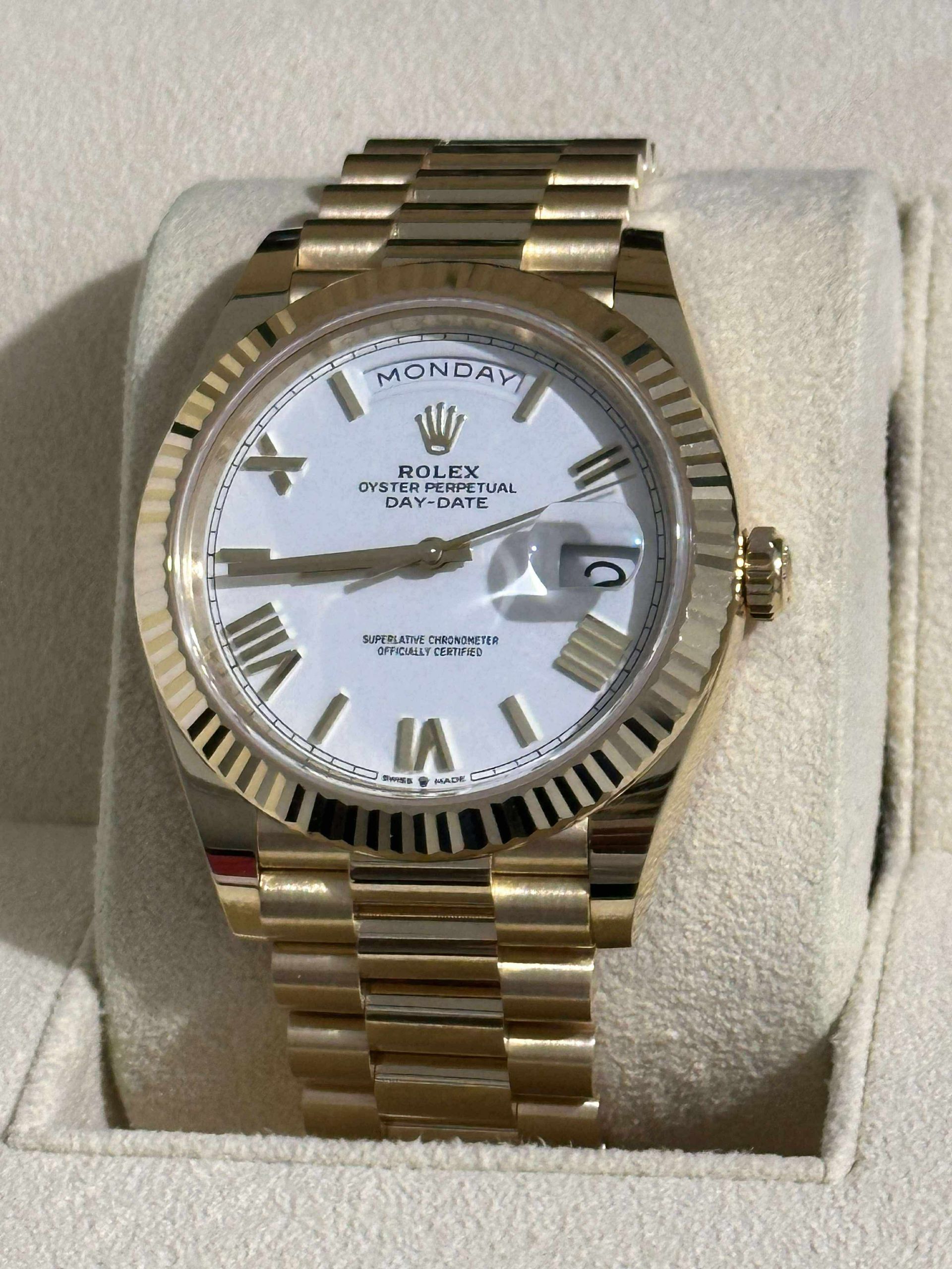 A silver and green rolex watch sits in a box