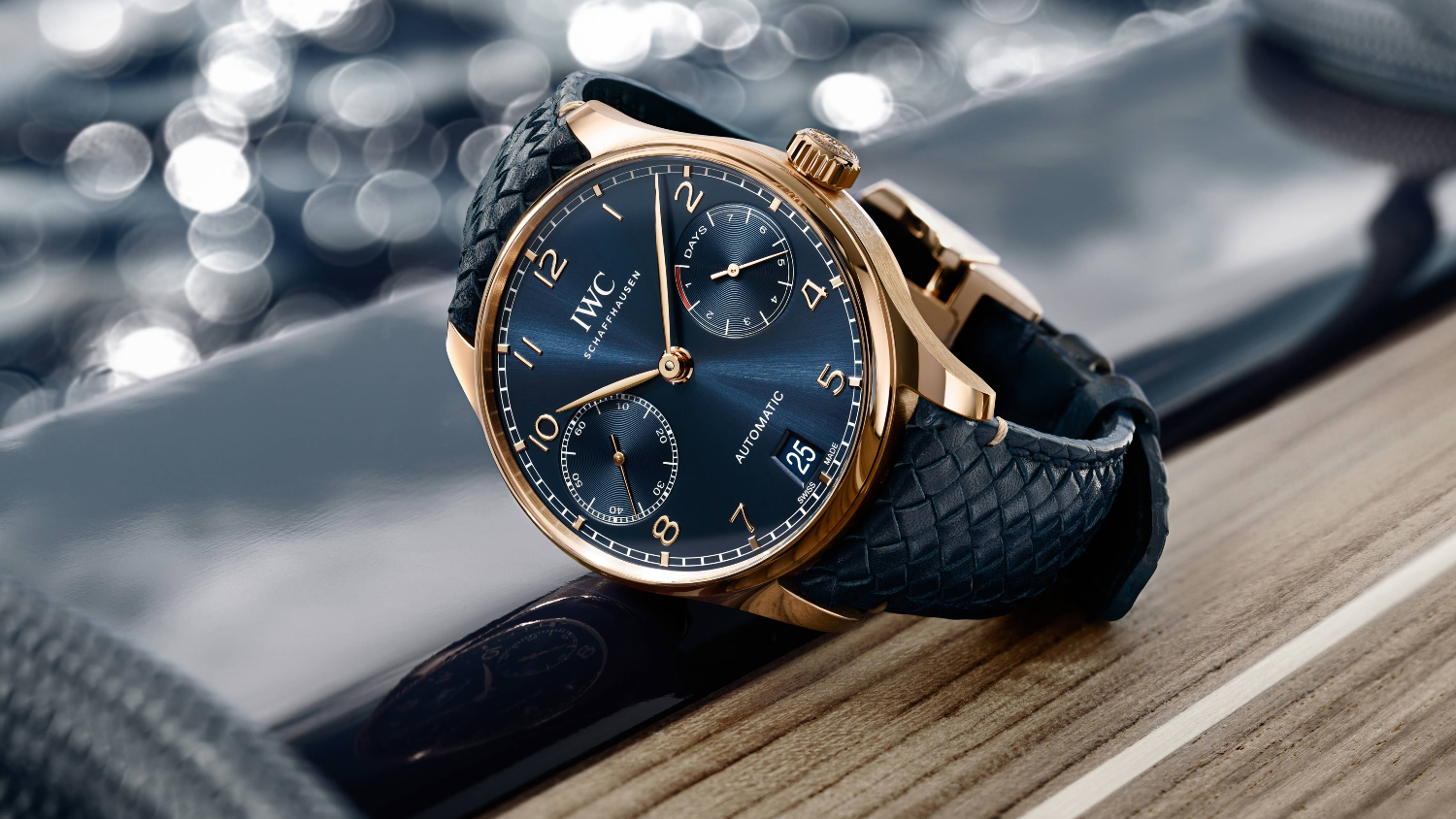 A watch with a blue face is sitting on a wooden table.