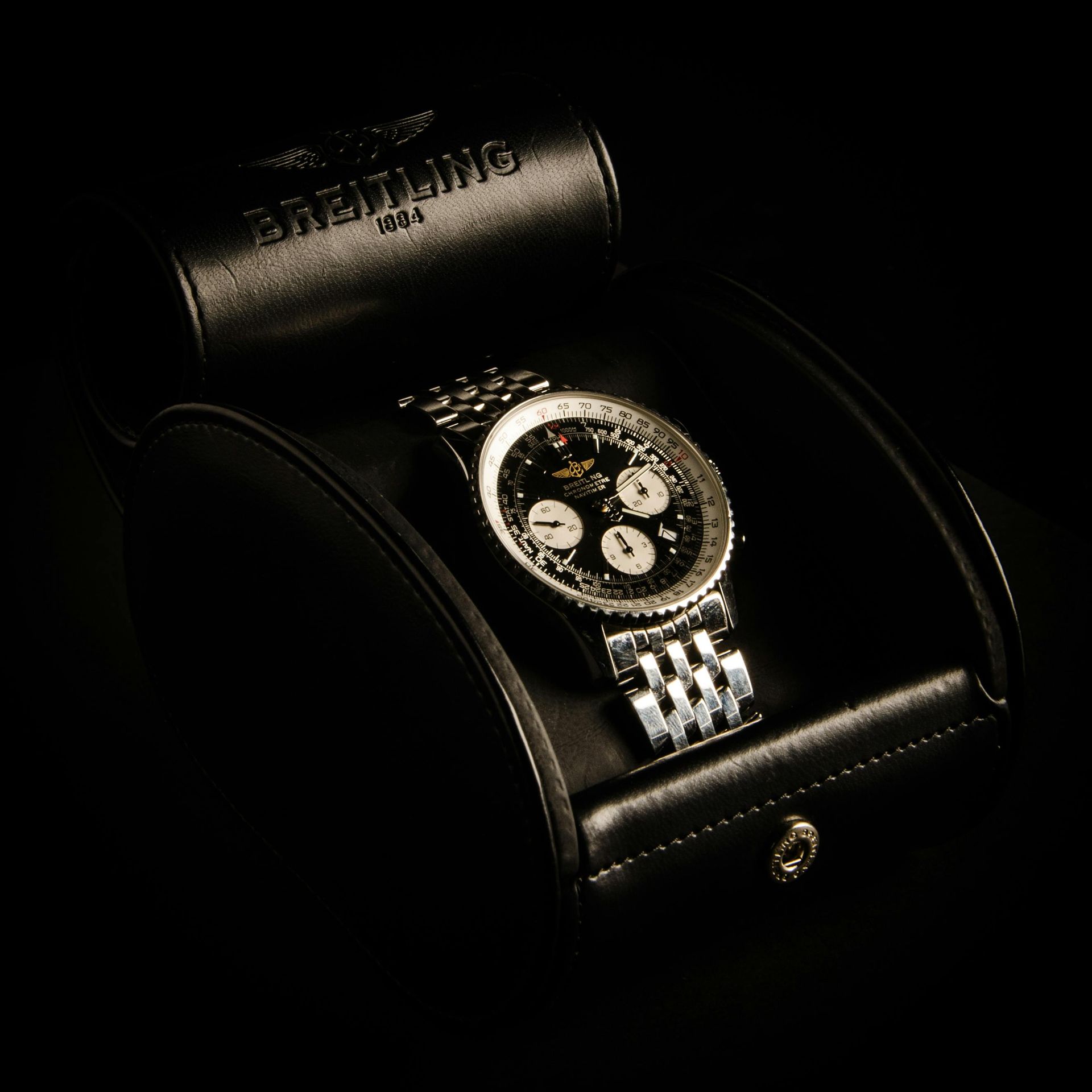 A breitling watch is in a black leather case
