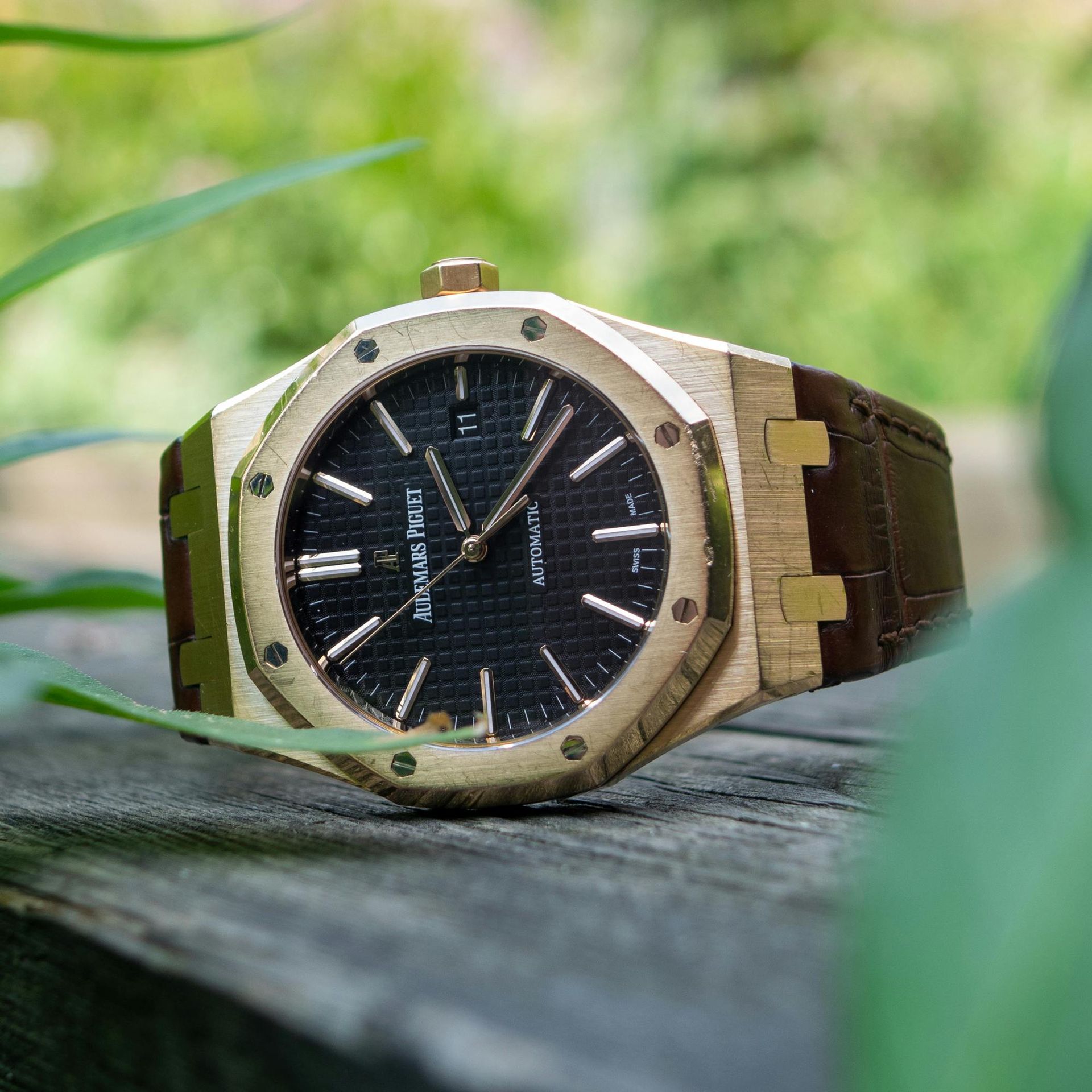 A gold audemars piguet watch is sitting on a wooden table.