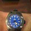 A person is wearing a black watch with a blue face on their wrist.