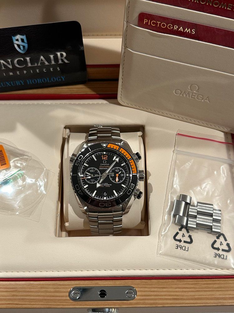 A watch is in a box with a wallet and a card.