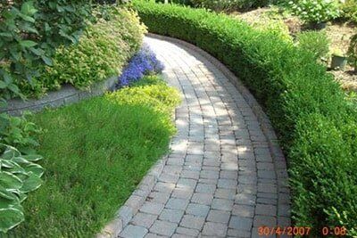 Stone Walkway With Bushes On Both Sides — Landscaping in Shelby Township, MI