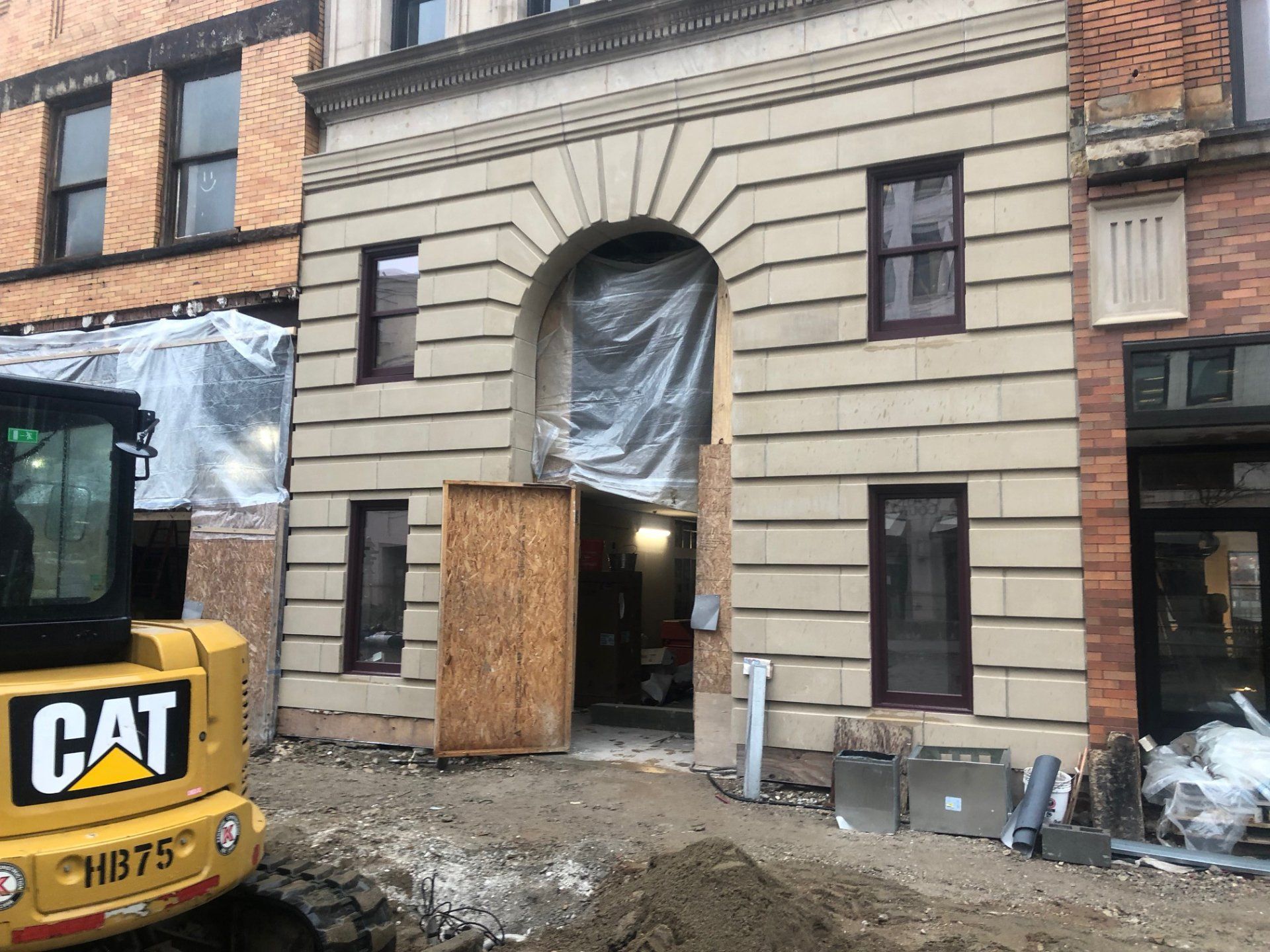 A cat excavator is parked in front of a building under construction.
