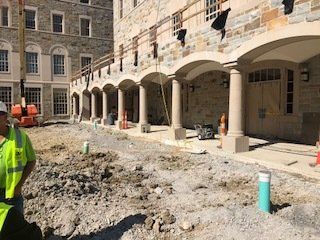 A construction worker is standing in front of a building under construction.