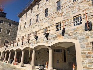 A large stone building with arches and columns is under construction.