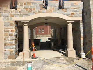 A stone building with columns and an archway is under construction.