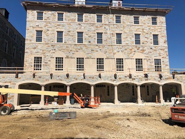 A large stone building under construction with a jlg lift in front of it