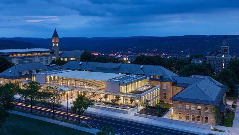 An aerial view of a large building at night with a clock tower in the background.