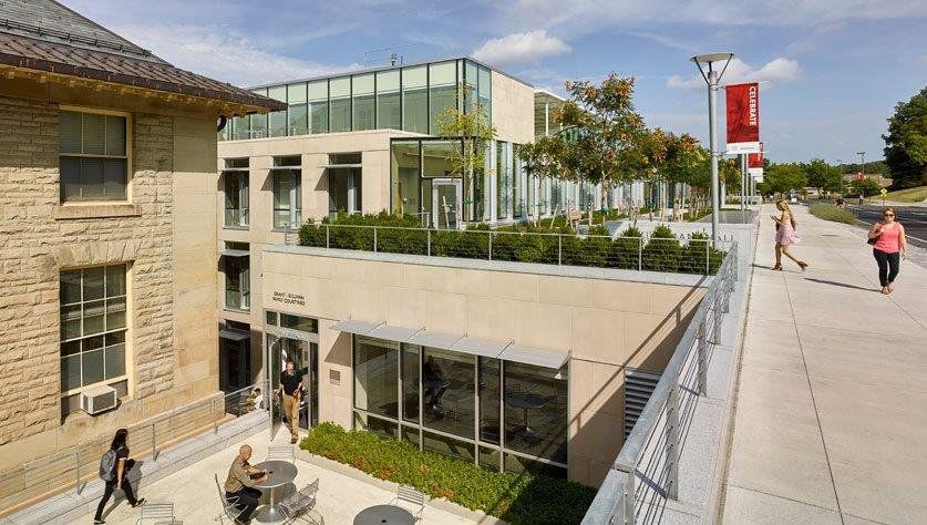 A group of people are walking down a sidewalk in front of a building.