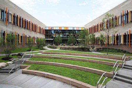 A large building with a lush green courtyard in front of it.