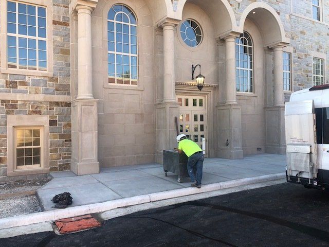A man in a yellow vest is standing in front of a building