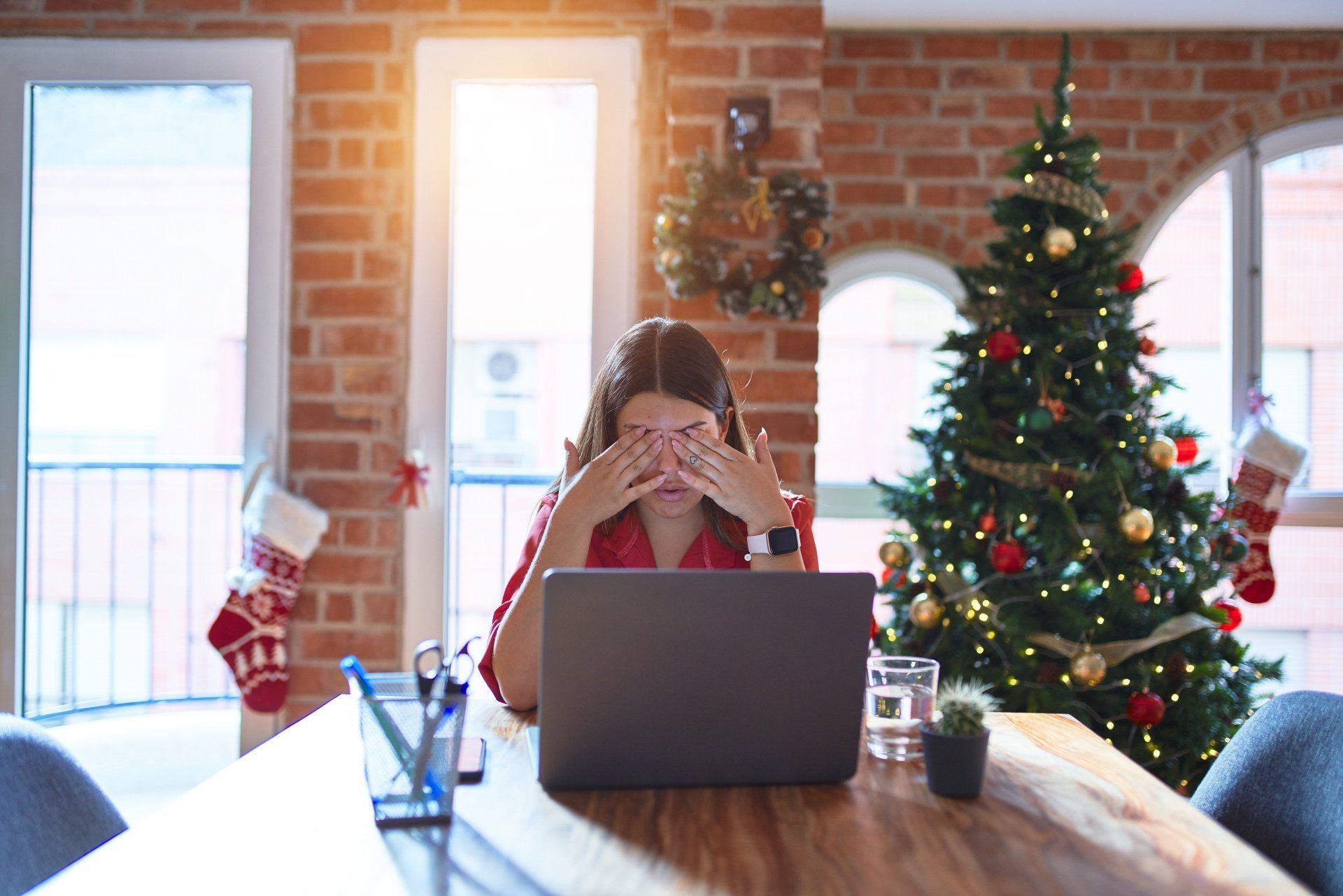Stressed-out woman in front of laptop with Christmas tree in the background