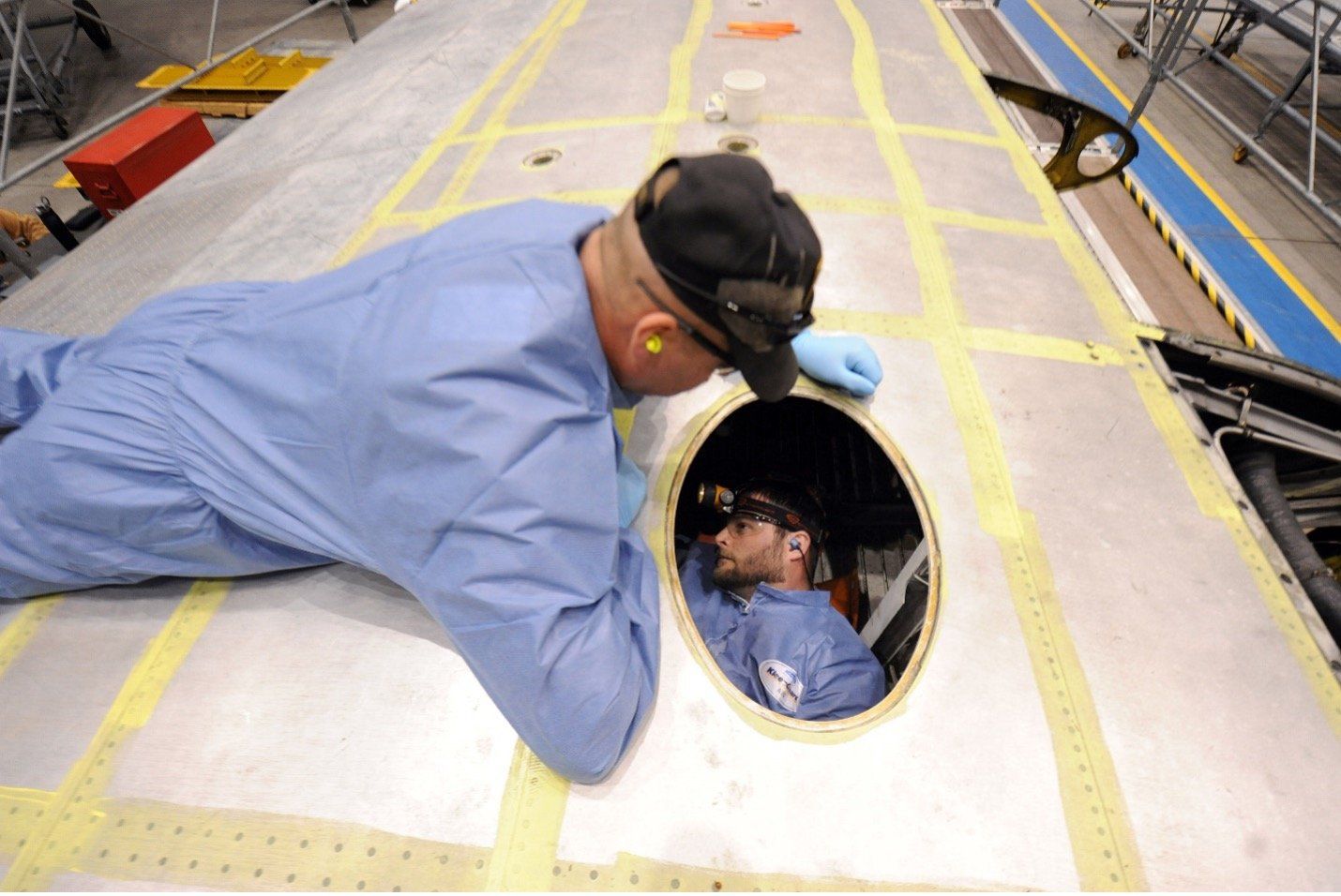 Man working in confined space while another watches.