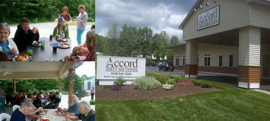 A group of people are sitting at a table in front of a building that says accord