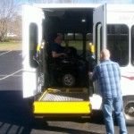 A man in a wheelchair is getting out of a bus.