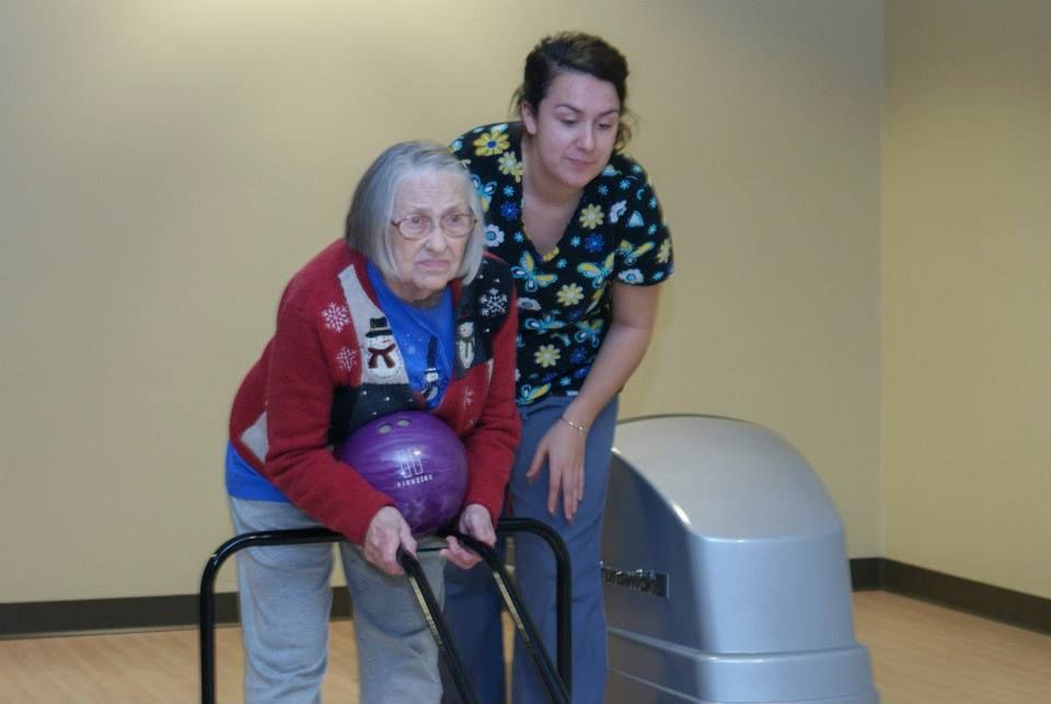 A nurse is helping an elderly woman in a wheelchair use a tablet computer.