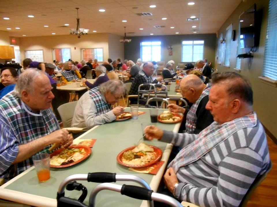 A woman is serving food to two elderly people in a restaurant.