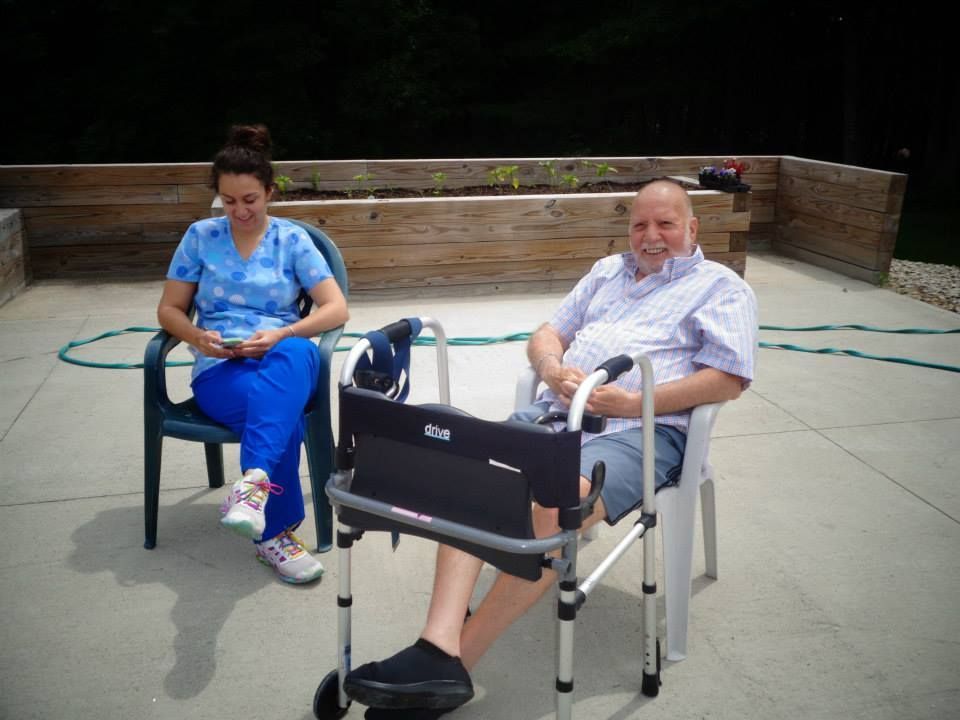 A nurse is giving an elderly man a glass of water.