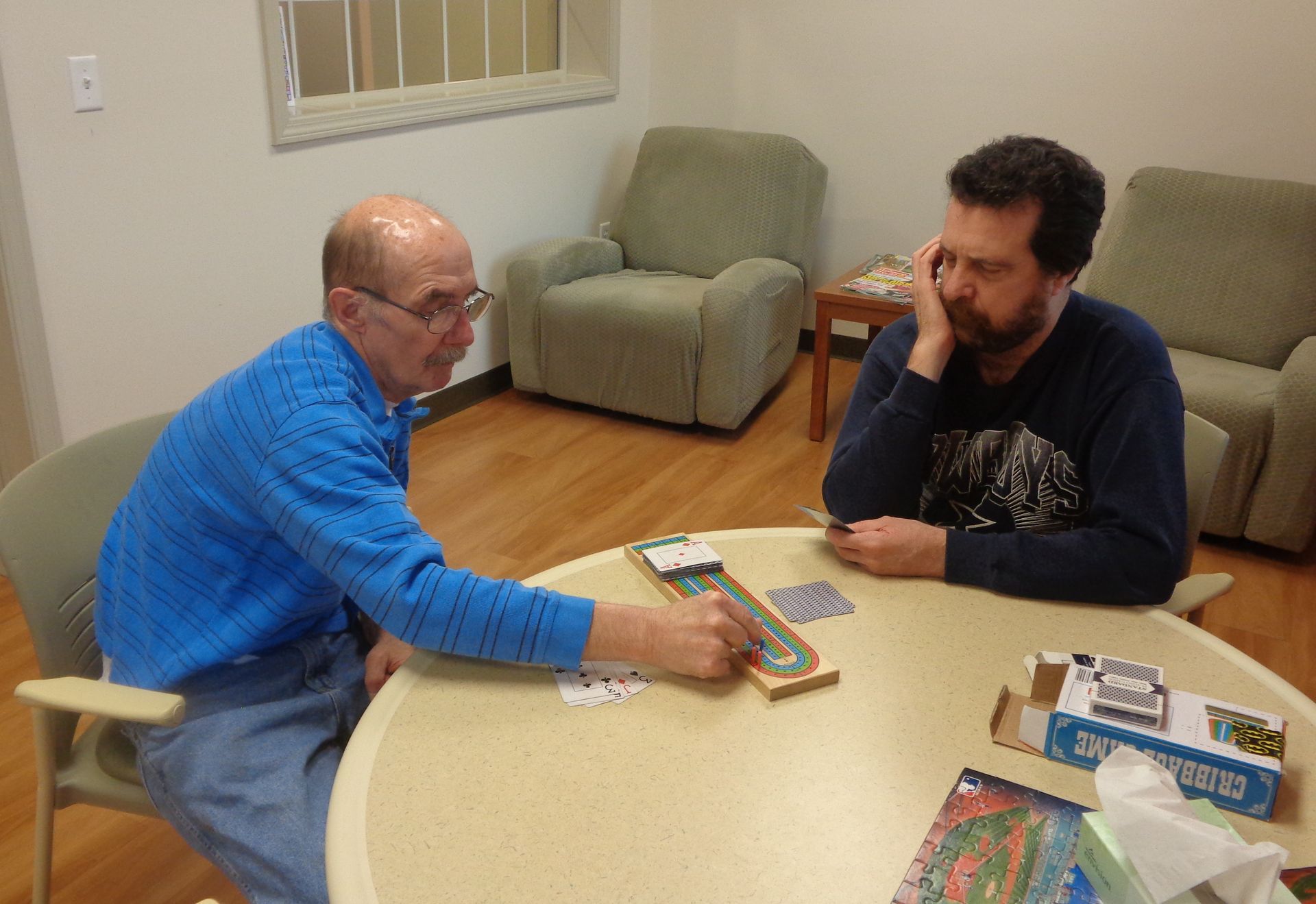 Two men are playing a game of scrabble at a table