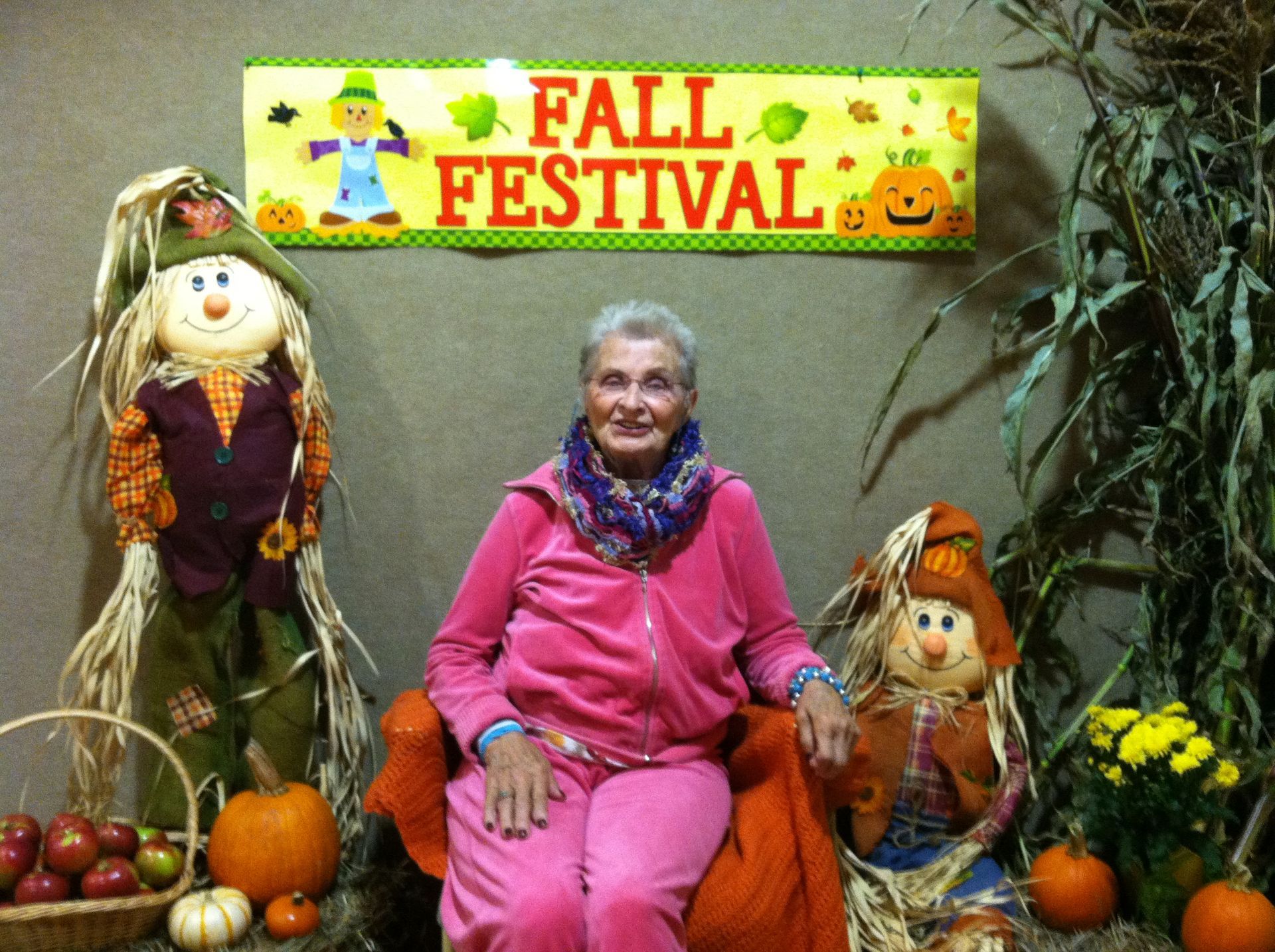 A woman sitting in front of a sign that says fall festival