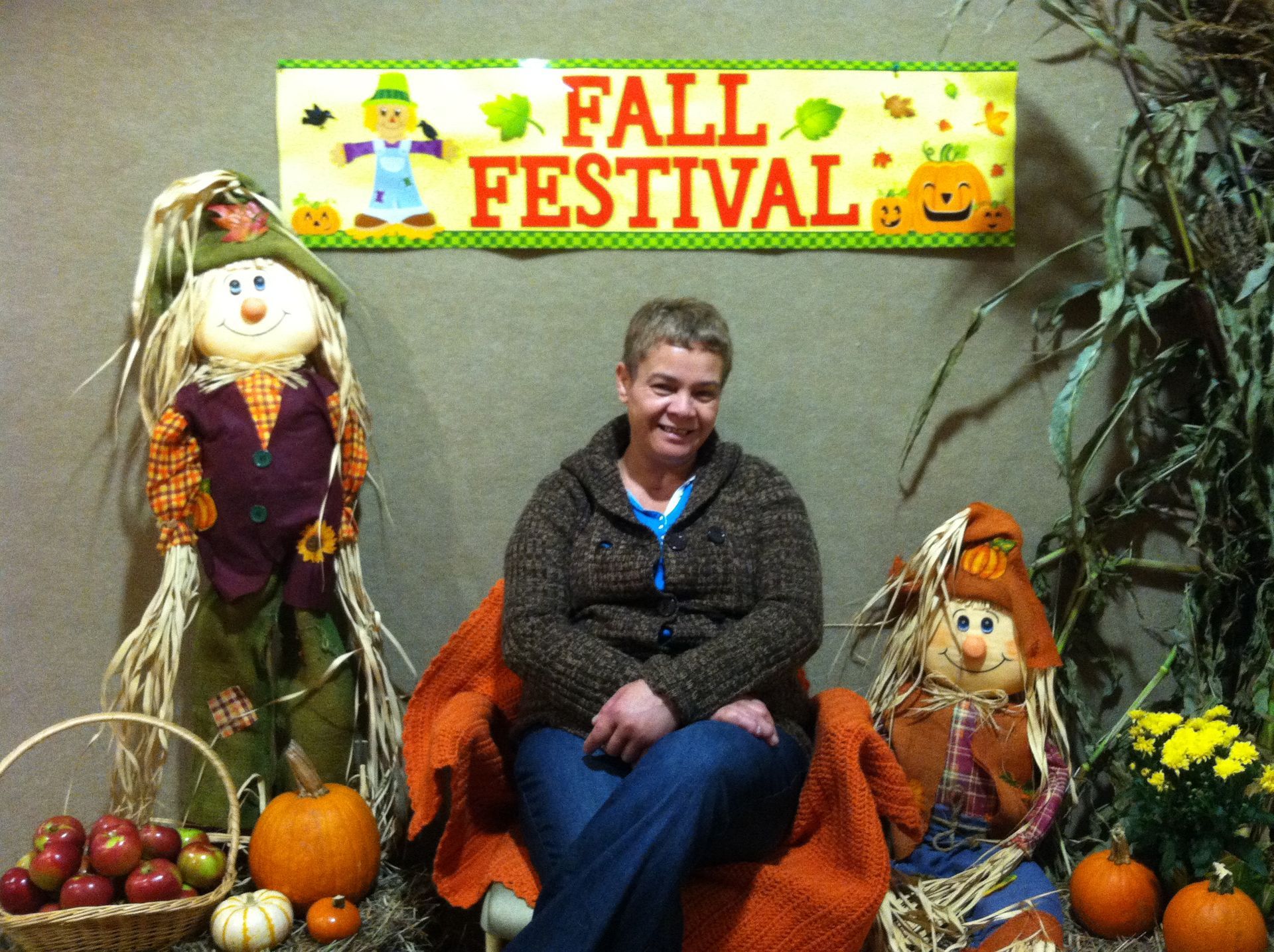A woman sits in front of a fall festival sign