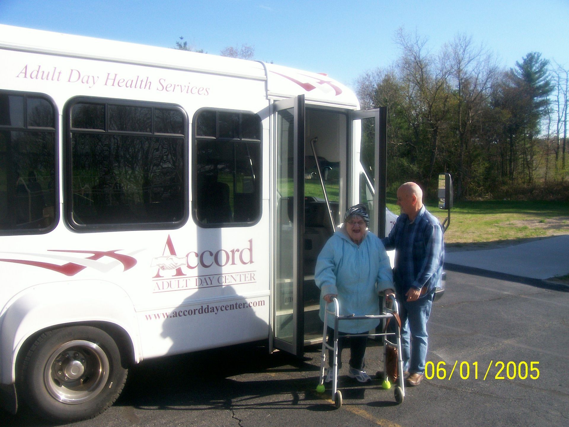 A woman in a wheelchair is getting on a white accord bus