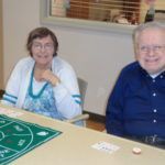A man and a woman are sitting at a table playing a game.