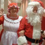 A woman dressed as mrs. claus and a man dressed as santa claus are posing for a picture.