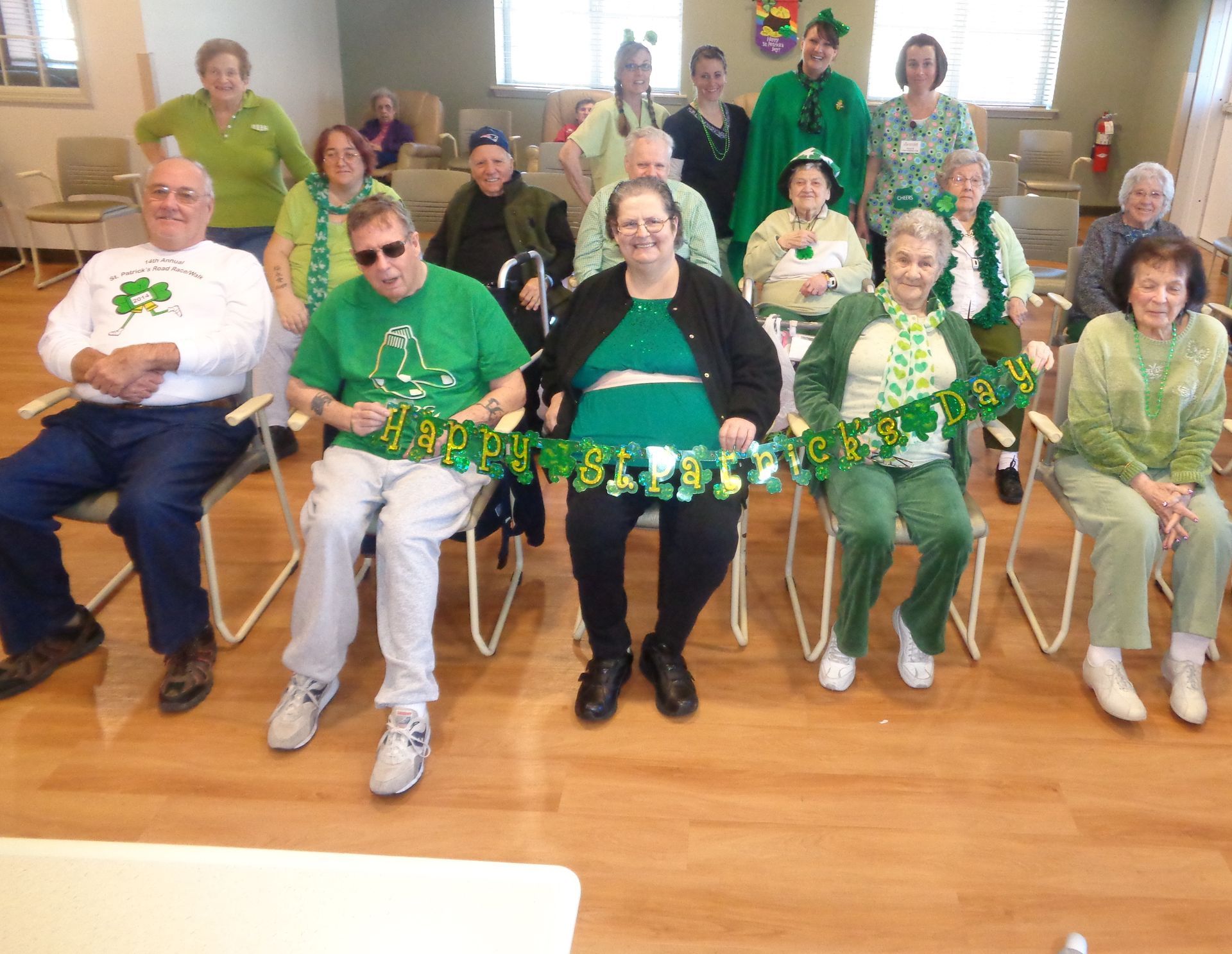 A group of people sitting in chairs holding a banner that says happy st. patrick 's day