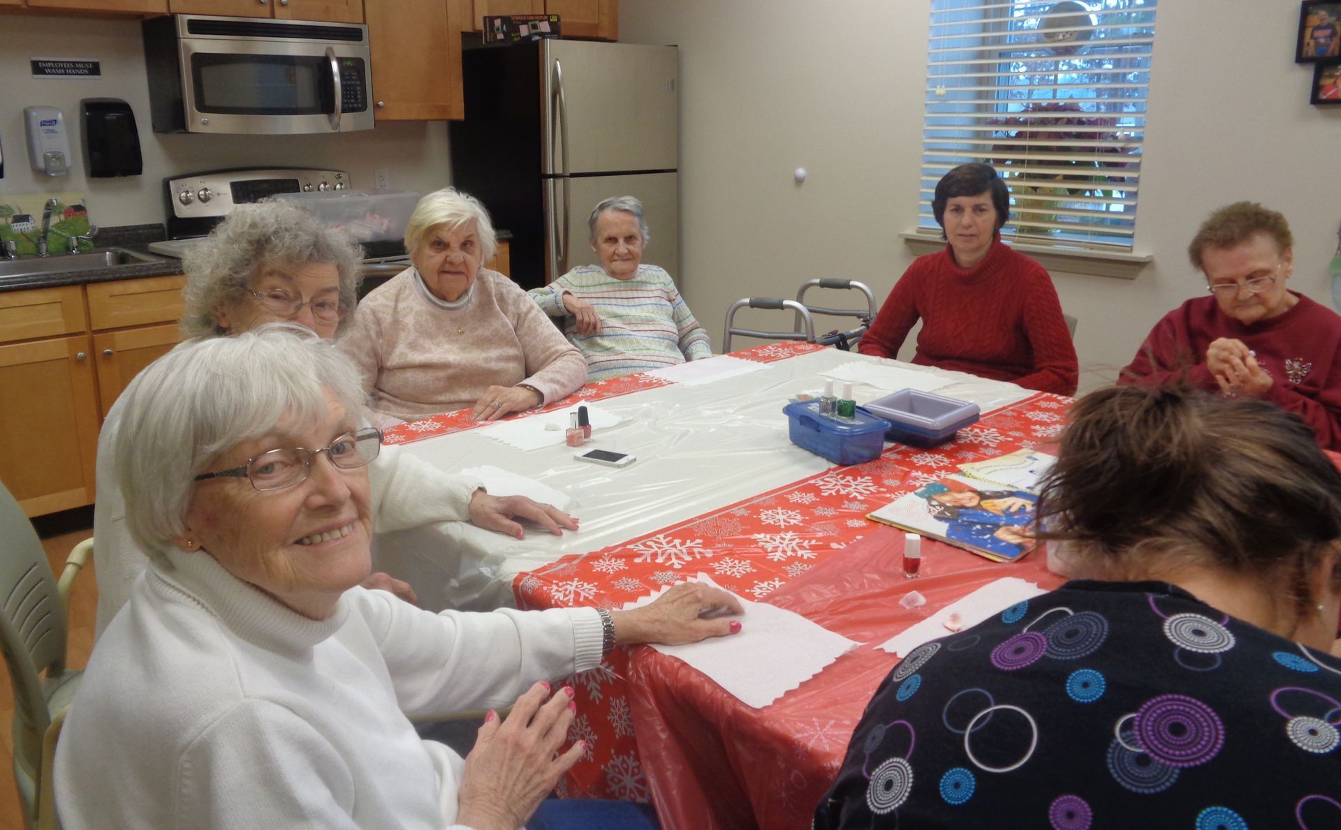 A group of elderly people are sitting around a table in a kitchen.
